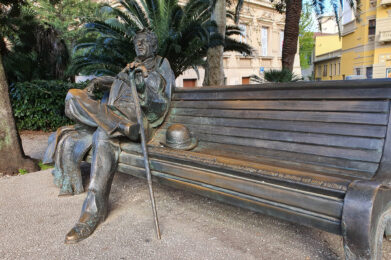 Monumento a Giacomo Puccini, scultura su panchina sotto gli alberi